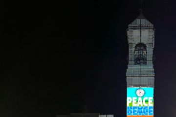 il campanile di San Vittore illuminato con simboli di pace