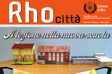 prima pagina di Rho città mese di marzo. A lezione nella nuova scuola. un tavolo con delle scuole in cartone colorare e un cartello con la trasformazione della scuola dal 1924 al 2026